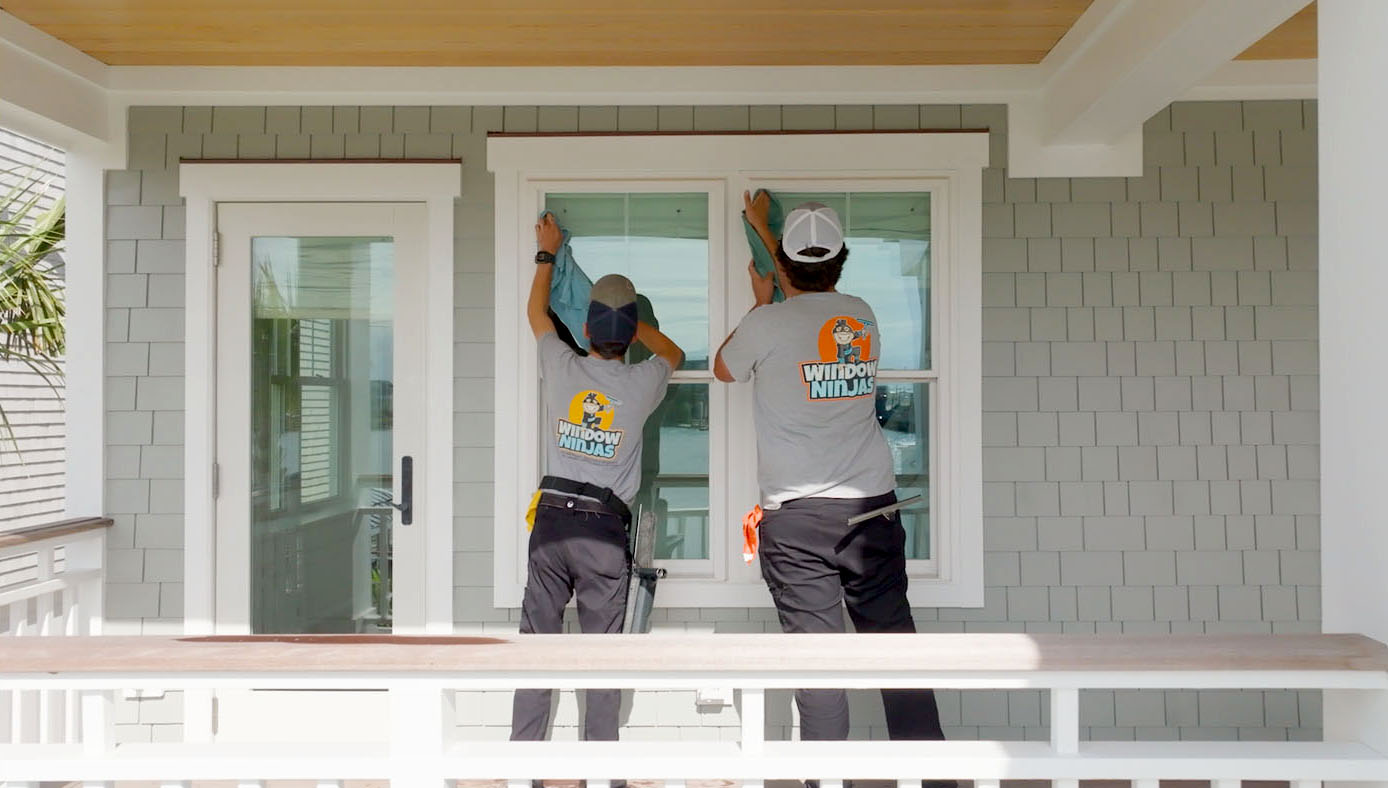 Two Window Ninjas technicians cleaning a house window. 